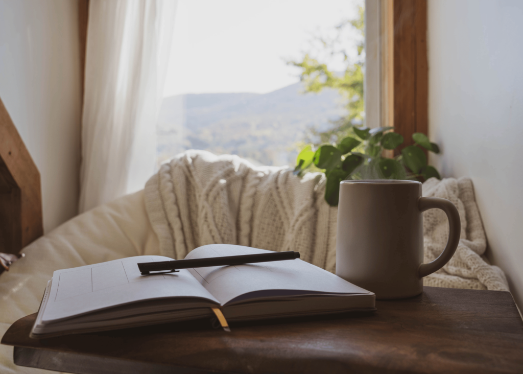 a calming photo of a desk by a sunny window with a plant, a cup of coffee and a to do list.....take time