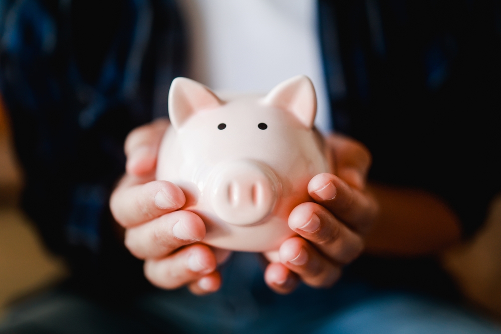 a person holding a piggy bank cupped in his/her hands.  