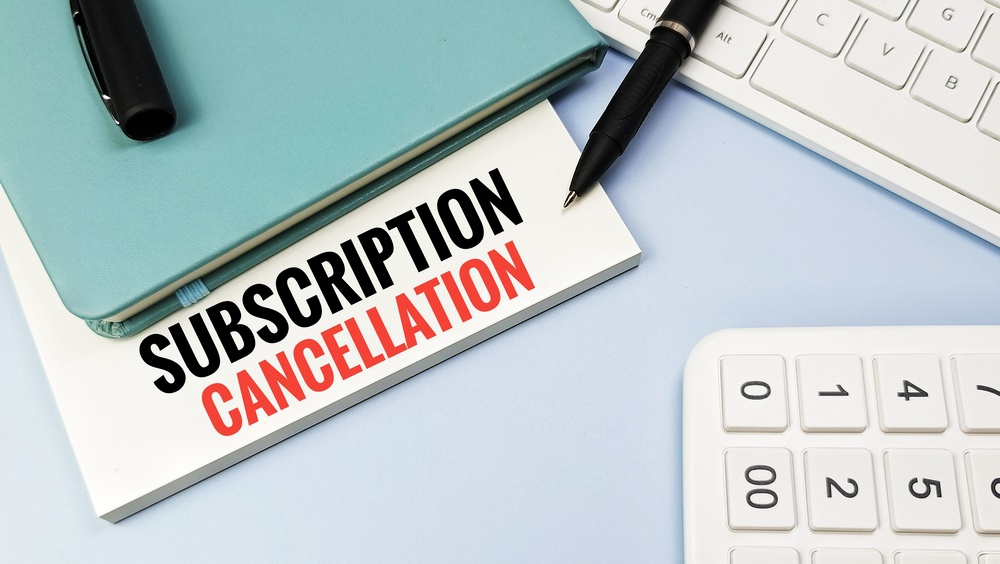 a calculator, notebook and pins with a paper saying subscription cancellation.