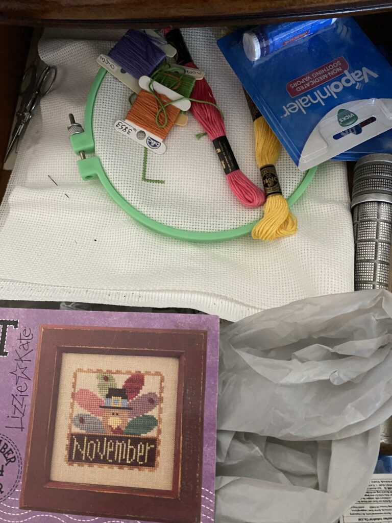 My Hello Spring cross stitch project waiting in the drawer. Image shows hoop, threads, needle, and another Lizzie Kate project for Thanksgiving.